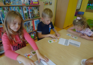 Dwójka dzieci dobiera podpisy do obrazków owoców.