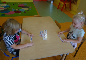 Dwie dziewczynki tworzą wyrazy z pierwszych głosek nazw obrazków.