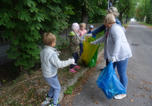 Dzieci wrzucają śmieci do worków, które trzyma pani Basia.