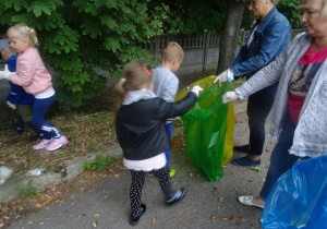 Dzieci wrzucają śmieci do worków, które trzymają pani Basia i pani Agnieszka.