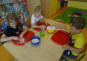 Dzieci wykonują doświadczenie z cieczą nienewtonowską, mieszają mąkę z wodą.