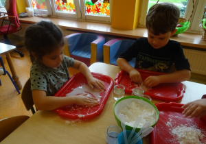 Dzieci wykonują doświadczenie z cieczą nienewtonowską, mieszają mąkę z wodą.