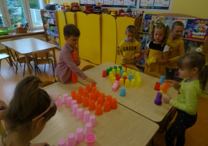 Dzieci układają ludzika z kolorowych kubków.