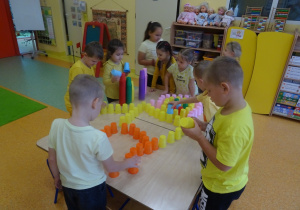 Dzieci układają ludzika z kolorowych kubków.