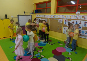 Dzieci tańczą w parach z balonem pomiędzy brzuchem z uniesionymi rękami.