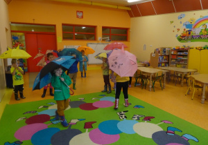 Dzieci tańczą z parasolkami.
