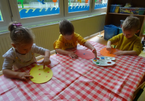 Dzieci stemplują szablony balonów palcami maczanymi w farbie.