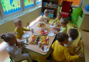 Dzieci jedzą owocowe przekąski.