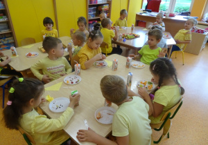 Dzieci jedzą owocowe przekąski.