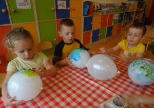Dzieci malują paluszkami maczanymi w farbie balony.