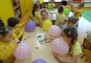 Dzieci rysują pisakami na balonach.