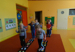 Dzieci chodzą po planszach z naklejonymi stopami.