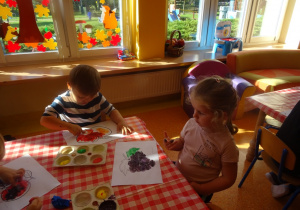 Dzieci malują farbami owoce.