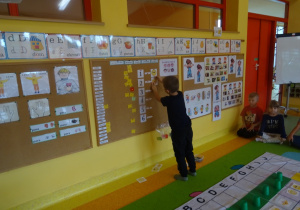 Chłopiec koduje tabliczki z emocjami za pomocą cyfr na tablicy.