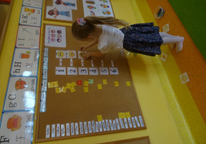Dziewczynka koduje tabliczki z emocjami za pomocą cyfr na tablicy.