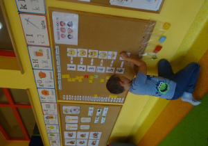 Chłopiec koduje tabliczki z emocjami za pomocą cyfr na tablicy.