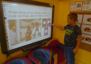 Chłopiec rozwiązuje quiz na tablicy interaktywnej, wskaźnik unosi w kierunku właściwej odpowiedzi.
