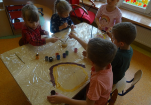 Piątka dzieci maluje na folii.