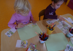 Dzieci układają historyjkę obrazkową, naklejają obrazki na kartkę papieru.