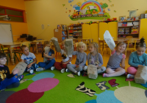 Dzieci pokazują emocje na woreczkach papierowych nałożonych na uniesioną dłoń.