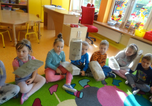 Dzieci pokazują emocje na woreczkach papierowych nałożonych na uniesioną dłoń.