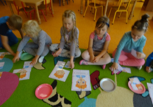 Piątka dzieci układa na dywanie obrazek z części.