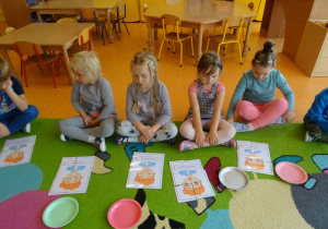 Piątka dzieci siedzi przed ułożonymi obrazkami z części.