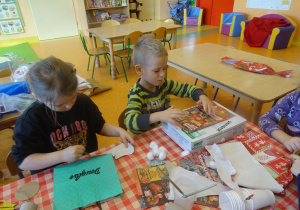Dwójka dzieci przygotowuje stroje ekologiczne z papierowych toreb, kartonu.