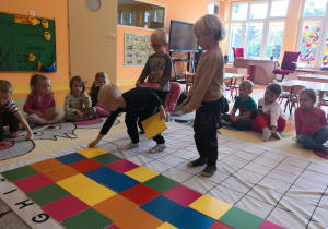 trzech chłopców kontynuuje rytm na macie, zaczęty przez nauczyciela - czerwony kwadrat, zielony kwadrat , żółty kwadrat itd.