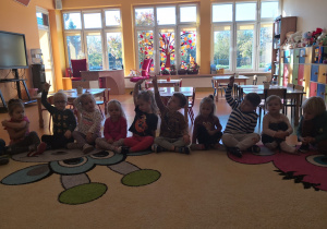dzieci siedzą na dywanie zgłaszają się
