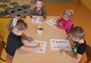 dzieci przy stolikach wykonują kartę pracy, łącza ptaki z ich cieniami