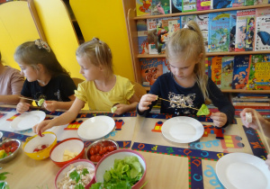 dzieci przy stolikach nadziewają na patyczki warzywa, nabiał tworząc szaszłyki