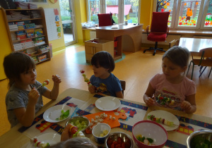 dzieci zajadają się zrobionymi przez siebie szaszłykami