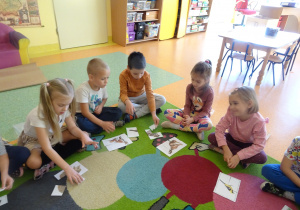 dzieci składały obrazek przedstawiający zwierzęta podzielony na części na dywanie