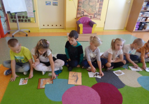 dzieci składały obrazek przedstawiający zwierzęta podzielony na części na dywanie