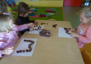 dzieci przy stolikach układały poznane litery z kasztanów