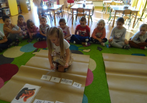 dzieci na dywanie układały zdania z rozsypanek wyrazowych w połączniu z ilustracjami