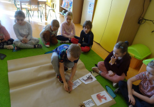 dzieci na dywanie układały zdania z rozsypanek wyrazowych w połączniu z ilustracjami i darami jesieni