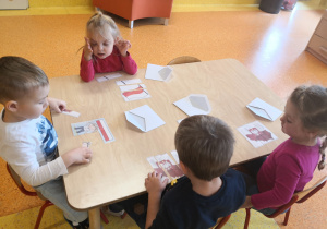 przy stolikach dzieci układają ilustracje pocięte na kawałki