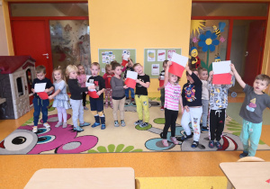 dzieci są podzielone na dwie grupy jedni trzymają białe kartki drudzy czerwone na sygnał nauczyciela ich zadaniem jest połączyć się w pary tworząc flagę Polski