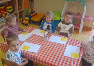dzieci przyklejają na kartkach żółty kwadrat na kartki