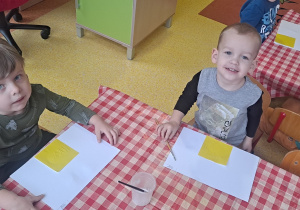 dzieci przyklejają na kartkach żółty kwadrat na kartki