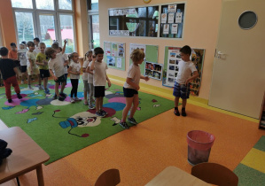 dzieci ustawieni w rzędzie jeden na drugim wykonują ćwiczenia gimnastyczne