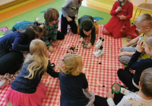 dzieci na dywanie na ceracie oglądają jak wygląda węgiel przy pomocy lup