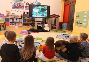 dzieci na dywanie oglądają prezentacje na temat "Pluszowego Misia"