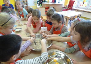 dzieci wrzucają i mieszają składniki na owsiane ciasteczka w misce