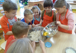 dzieci wrzucają i mieszają składniki na owsiane ciasteczka w misce