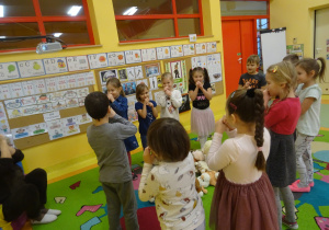 dzieci śpiewają i pokazują piosenkę wg poleceń nauczyciela przebranego za pluszowego misia