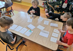 dzieci układają bałwanki przy stolikach w odpowiedniej kolejności