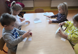 dzieci przy stolikach układają bałwanki w odpowiedniej kolejności